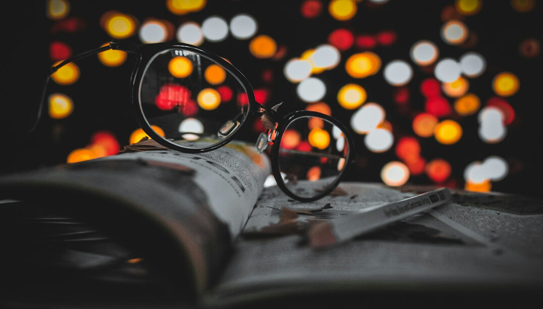 Open book with a pair of glasses on a table